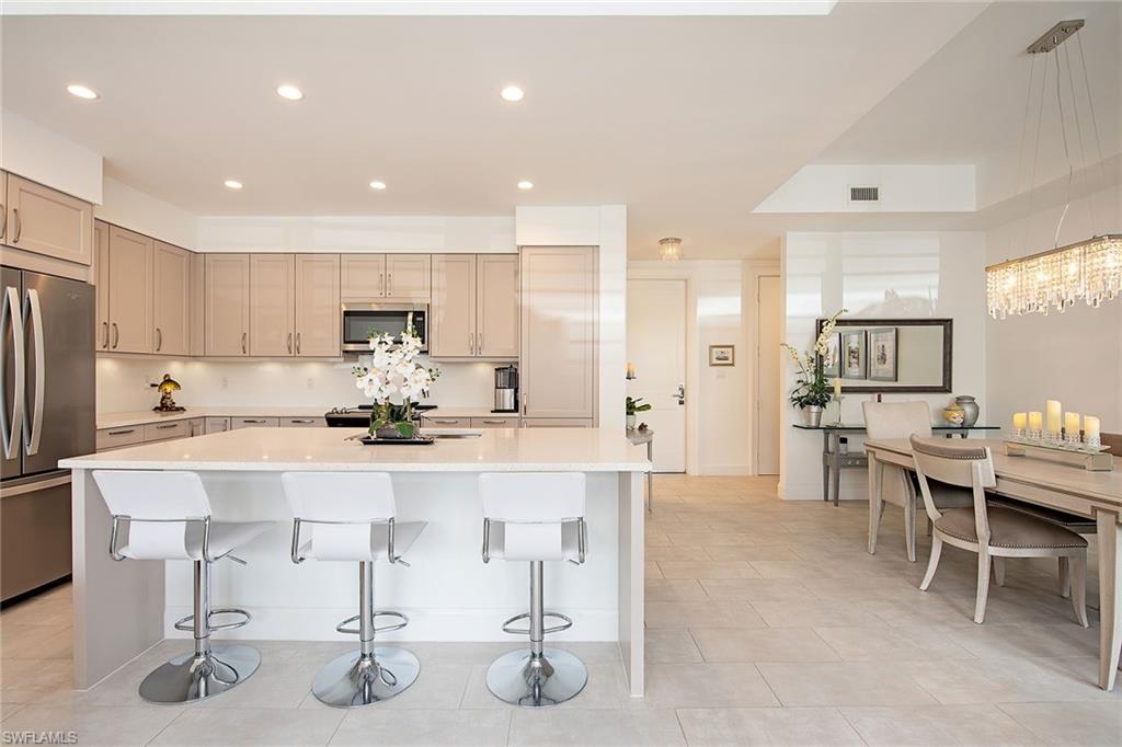 1111 Central Avenue, Unit 207 Naples, FL 34102 - Photo 7 of 18 a view of a kitchen with kitchen island stainless steel appliances a table and chairs in it