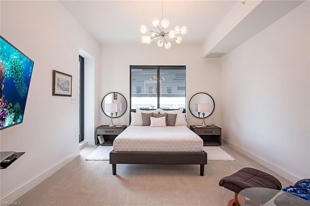 1111 Central Avenue, Unit 207 Naples, FL 34102 - Photo 8 of 18 a living room with furniture a clock and a large window