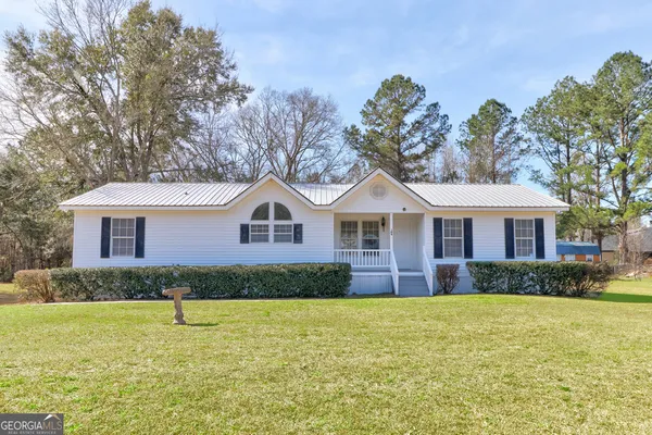 a front view of a house with a yard and trees