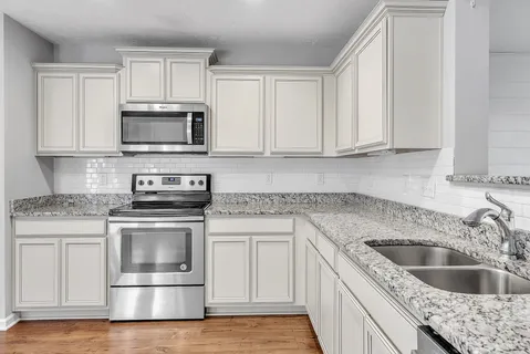 a kitchen with granite countertop a sink stove and microwave