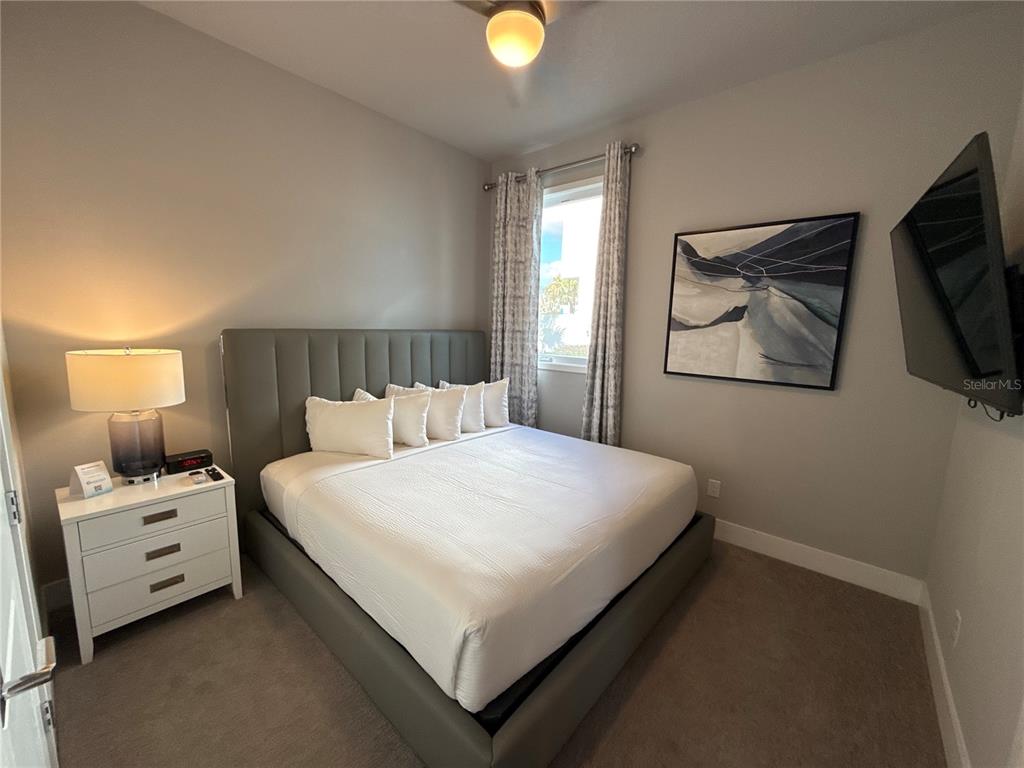 7740 Sandy Ridge Drive, Unit 120 Reunion, FL 34747 - Photo 25 of 36 a bedroom with a bed and a flat tv screen on the dresser