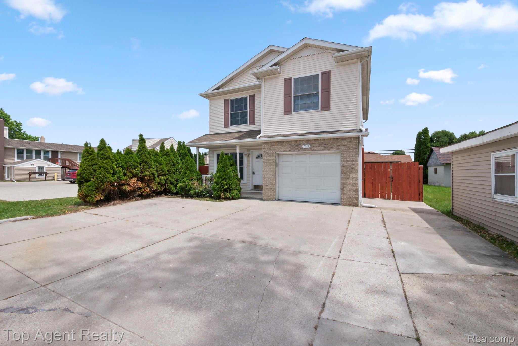 2018 John R Road Troy, MI 48083 - Photo 30 of 30 View of front of home featuring a garage, a gate, driveway, brick siding, and covered porch