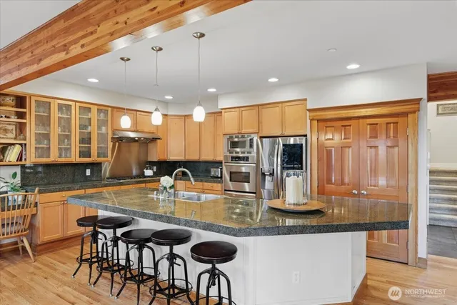 a kitchen with granite countertop kitchen island stainless steel appliances a sink and cabinets