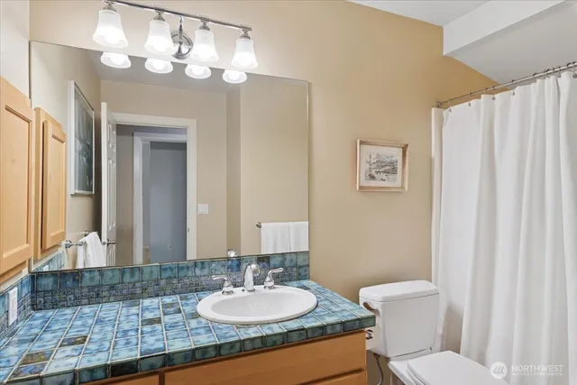a bathroom with a granite countertop sink a toilet and a mirror