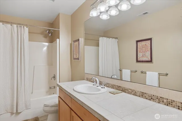a bathroom with a granite countertop sink a toilet and a mirror