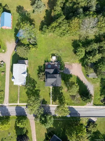 a view of house with a big yard and large trees