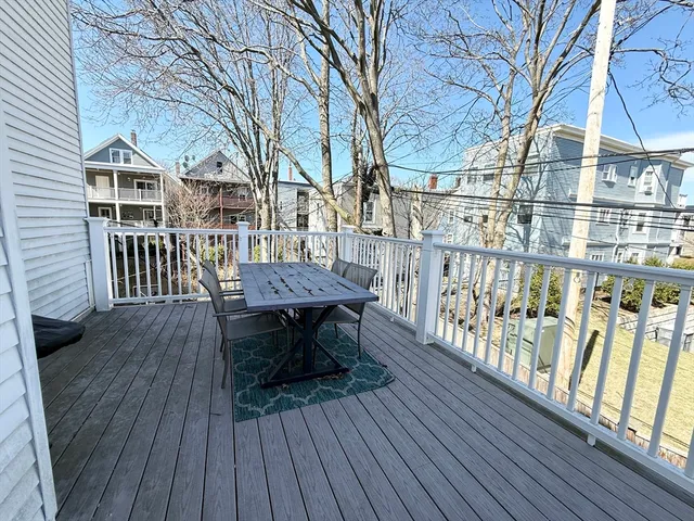 a view of a roof deck with table and chairs with wooden floor and fence