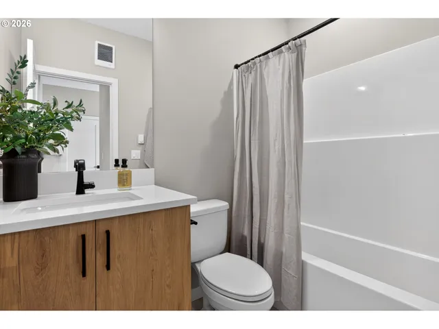 a bathroom with a sink a toilet a mirror and shower