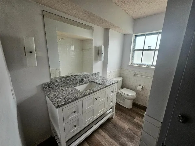 a bathroom with a granite countertop sink a toilet and mirror