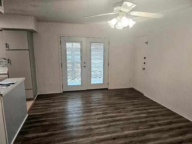 a view of an empty room with window and wooden floor