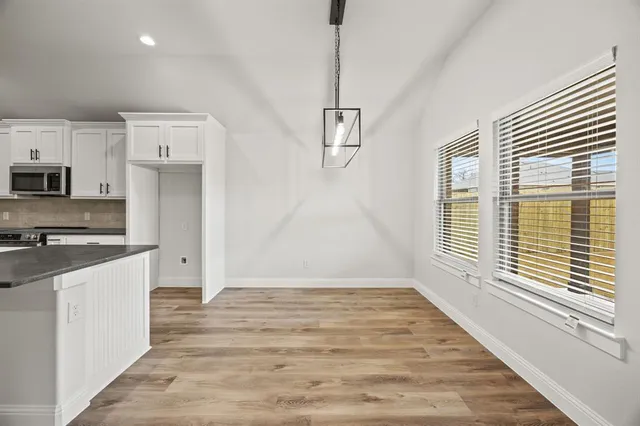 a large kitchen with stainless steel appliances granite countertop a stove a sink and a wooden floor