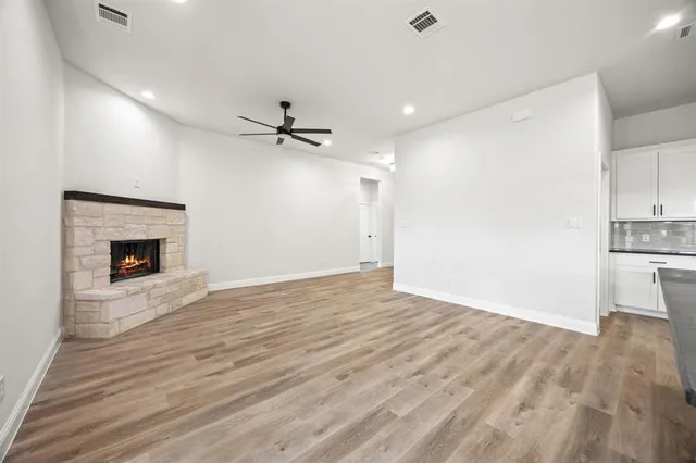 a view of a livingroom with a fireplace a ceiling fan and wooden floor