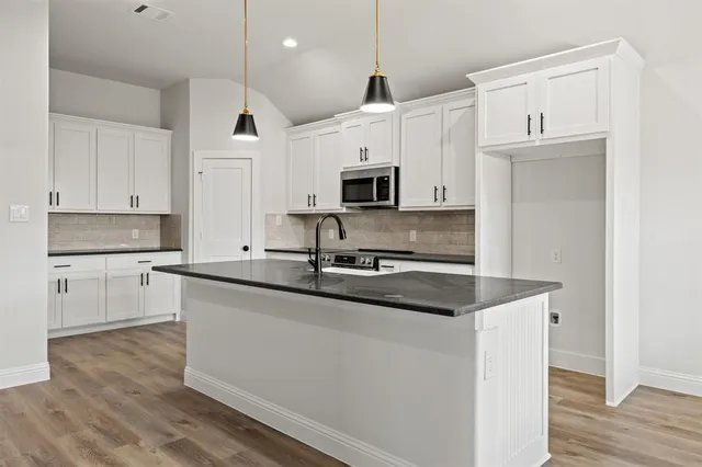 a kitchen with kitchen island white cabinets and stainless steel appliances