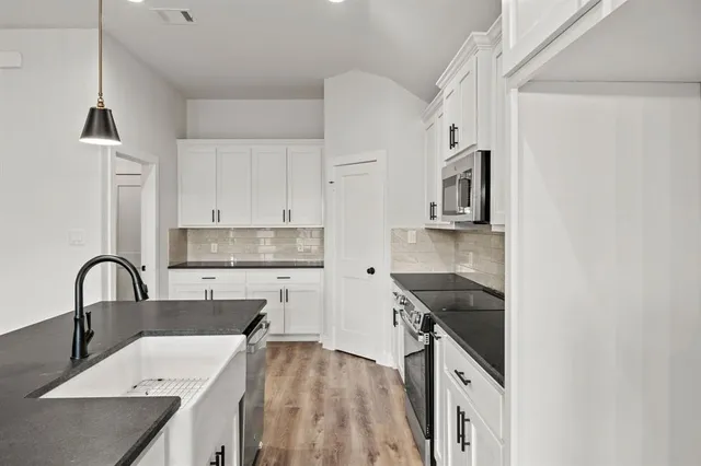 a open kitchen with a sink a large window and wooden floor