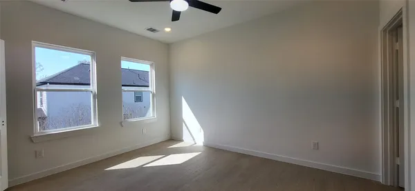 an empty room with windows and fan