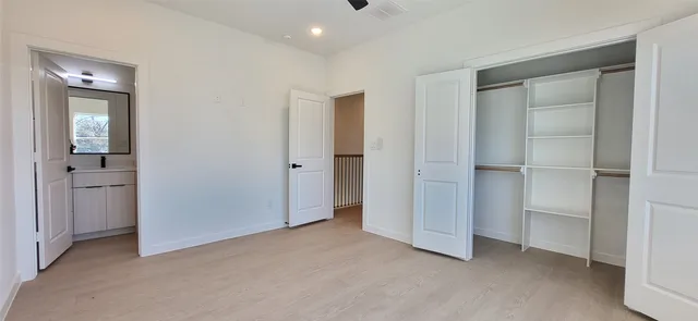 a view of an empty room with closet and wooden floor