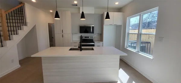 a kitchen with stainless steel appliances kitchen island a refrigerator sink and cabinets