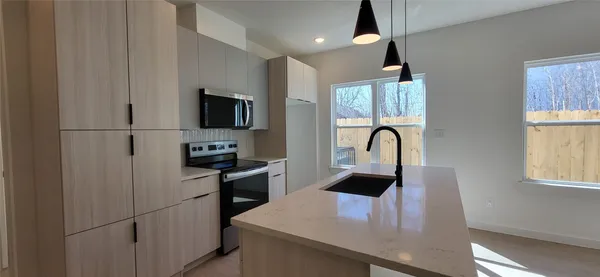 a view of kitchen with kitchen island a sink wooden floor and stainless steel appliances
