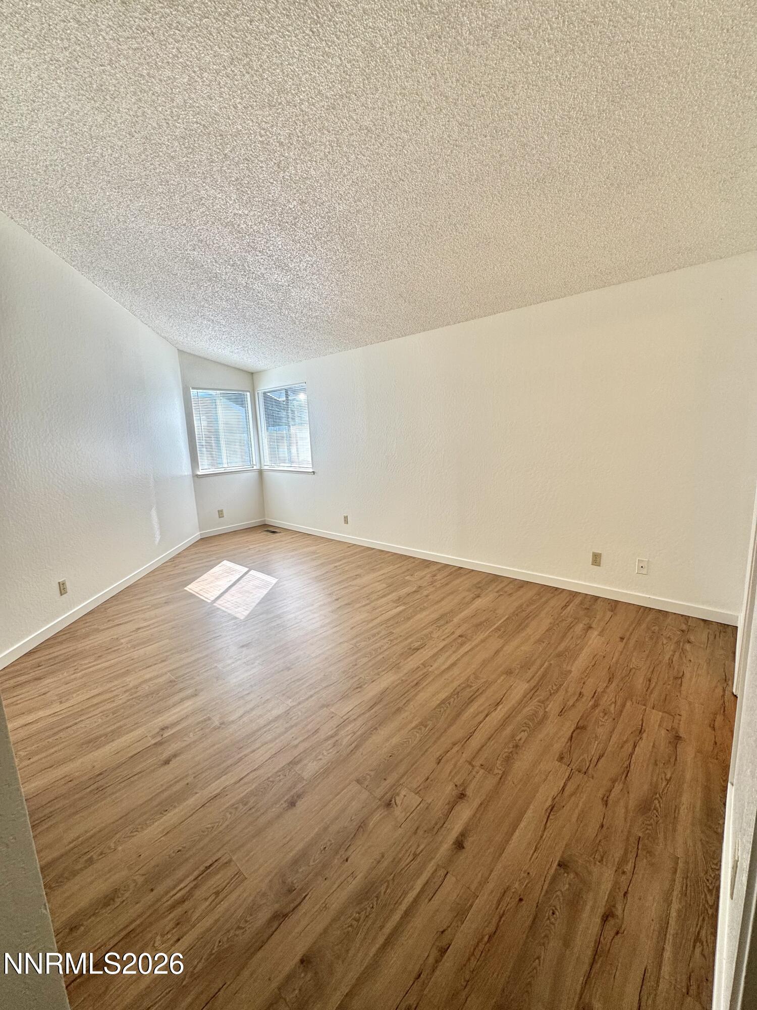 6052 Walnut Creek Road Reno, NV 89523 - Photo 6 of 11 an empty room with wooden floor and windows