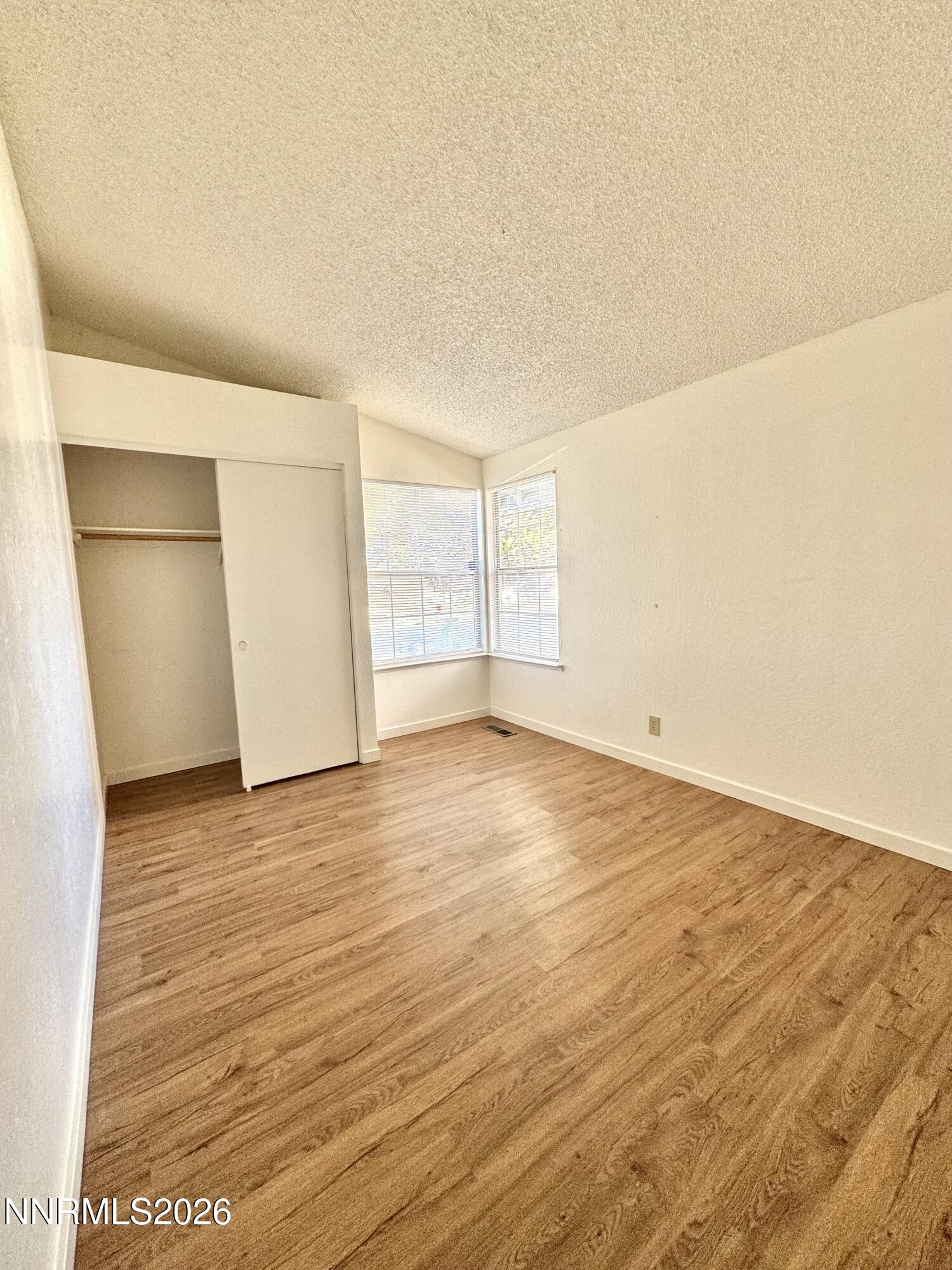 6052 Walnut Creek Road Reno, NV 89523 - Photo 9 of 11 an empty room with wooden floor and windows