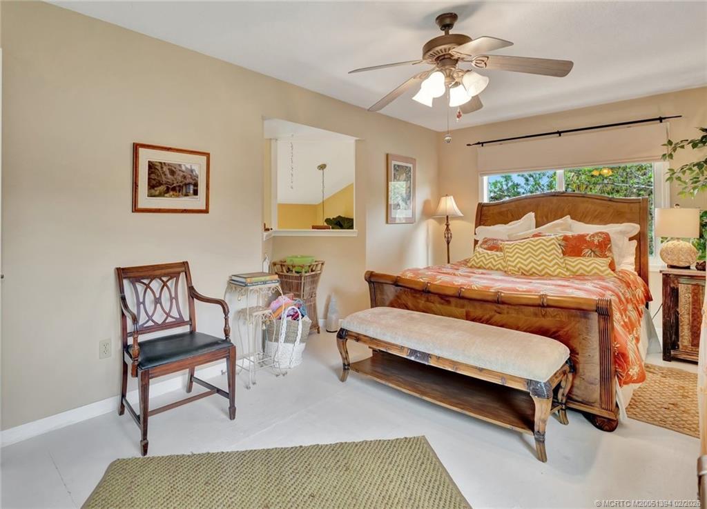 221 Coconut Avenue Stuart, FL 34996 - Photo 13 of 20 a bedroom with a bed a chair and a chandelier