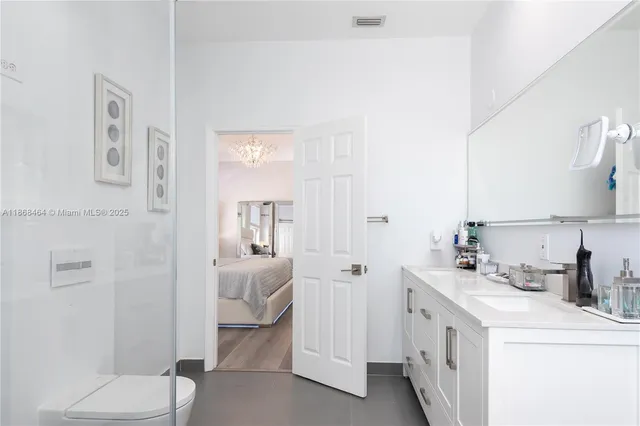 a bathroom with a double vanity sink toilet mirror and shower