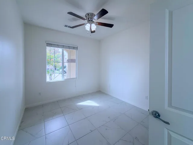 an empty room with a window and a fan