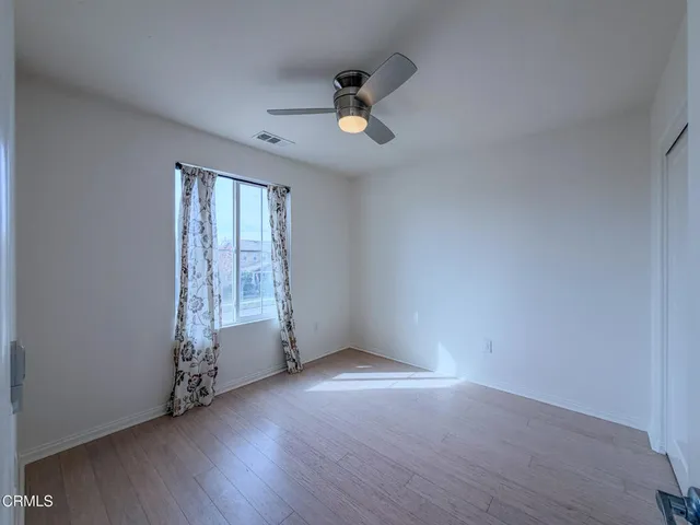 an empty room with wooden floor fan and windows