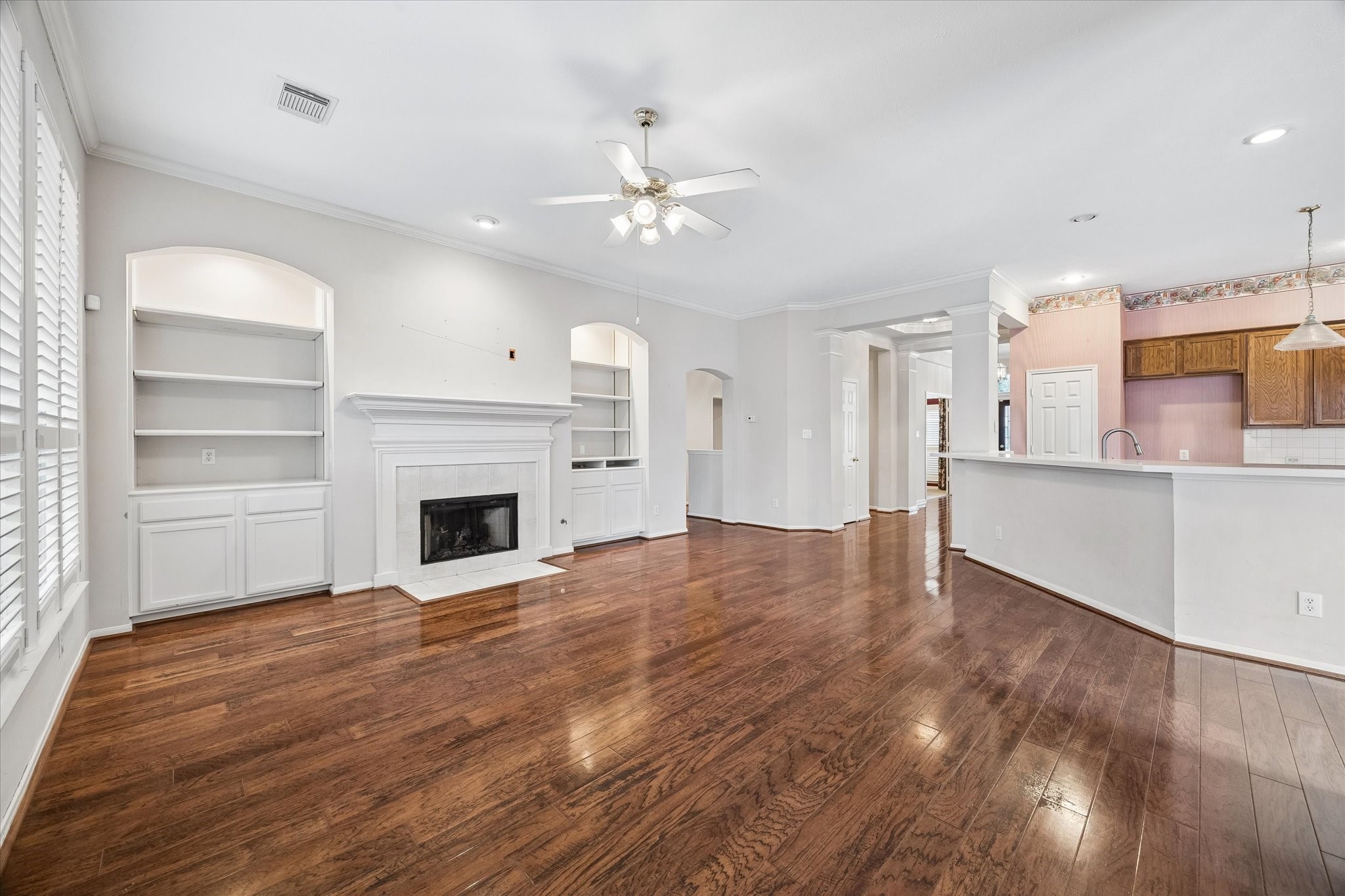 1203 Bingle Road Houston, TX 77055 - Photo 6 of 21 Spacious living area with rich hardwood floors, a cozy fireplace, and built-in shelving, seamlessly connecting to a bright kitchen with ample counter space.