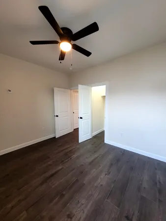 an empty room with wooden floor chandelier fan and windows