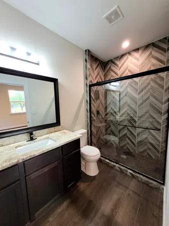 a bathroom with a granite countertop sink toilet and shower