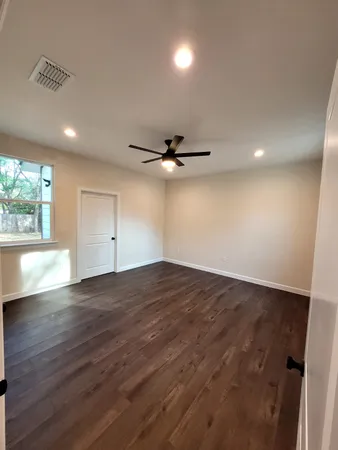 an empty room with wooden floor and windows