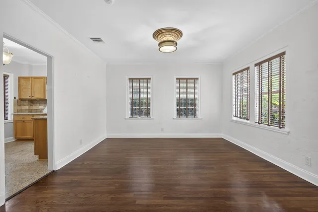 a view of an empty room with wooden floor and window
