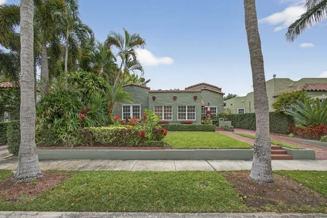 a front view of a house with a yard and potted plants