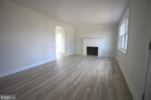 an empty room with wooden floor fireplace and windows