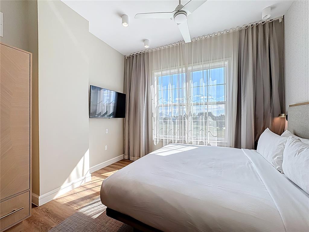 3151 Sunset Walk Drive, Unit 204 Kissimmee, FL 34747 - Photo 23 of 58 a bedroom with a large bed and a flat tv screen
