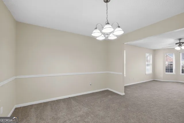 a view of an empty room with a chandelier fan