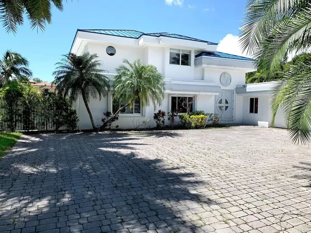 a view of a white house with a yard and palm trees