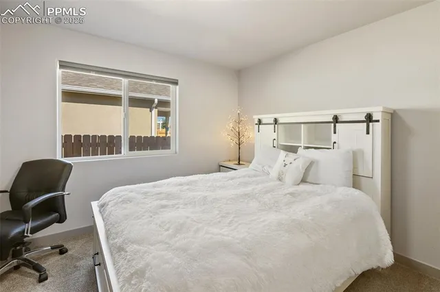 a bedroom with a bed windows and chair