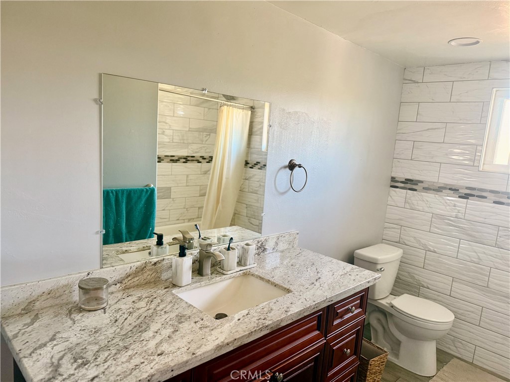 5982 Harrison Street Chino, CA 91710 - Photo 31 of 43 a bathroom with a granite countertop sink a toilet and a mirror