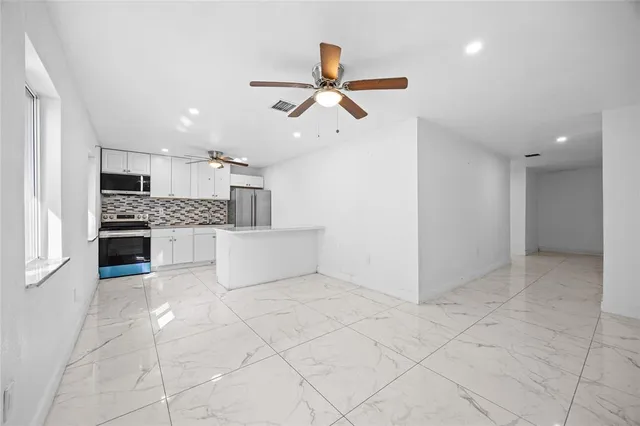 a kitchen with granite countertop a refrigerator and white cabinets