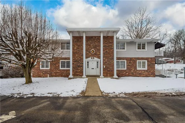 a front view of a house with a yard covered with snow