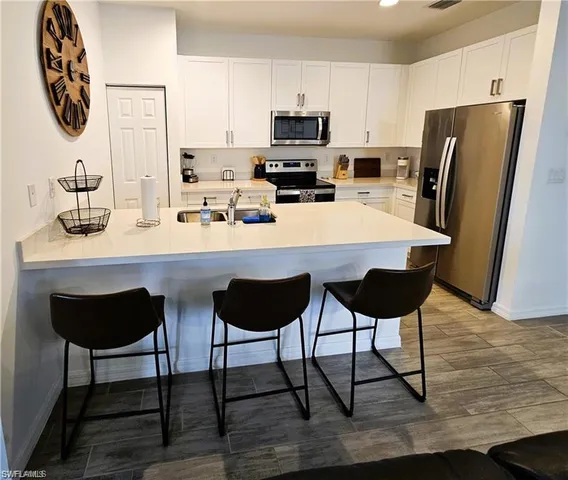 a kitchen with stainless steel appliances a dining table chairs and a refrigerator