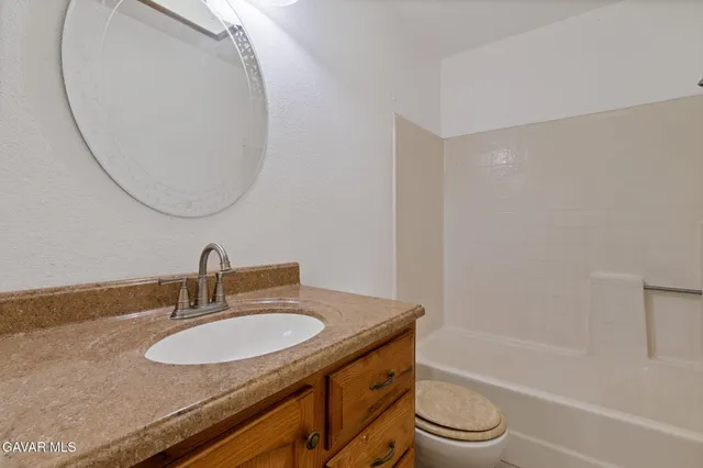 a bathroom with a granite countertop sink toilet and a mirror