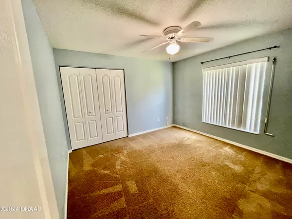 an empty room with windows and fan