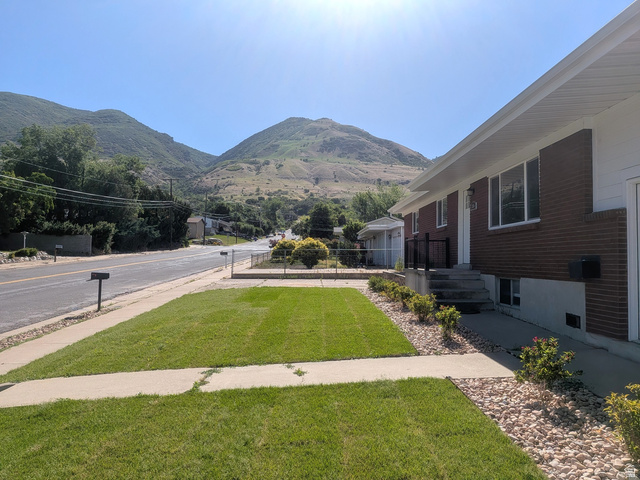 360 400 North Centerville, UT 84014 - Photo 3 of 30 Brick exterior with white trim, featuring a manicured lawn, concrete pathway, and a rock-landscaped bed with established shrubs
