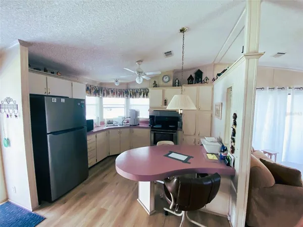 a kitchen with stainless steel appliances granite countertop a refrigerator a sink a stove a dining table and chairs