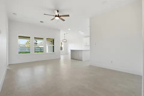 an empty room with windows and ceiling fan