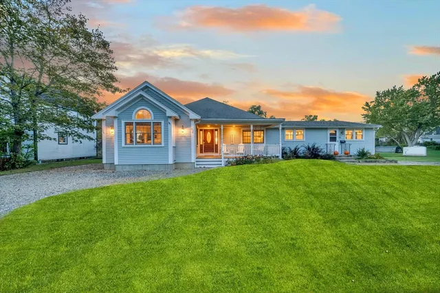 a front view of a house with a yard and trees
