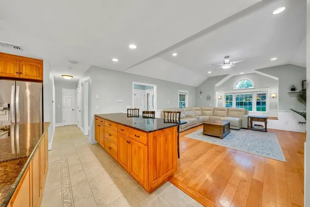 a large living room with stainless steel appliances granite countertop lots of white furniture a rug kitchen view and a large window